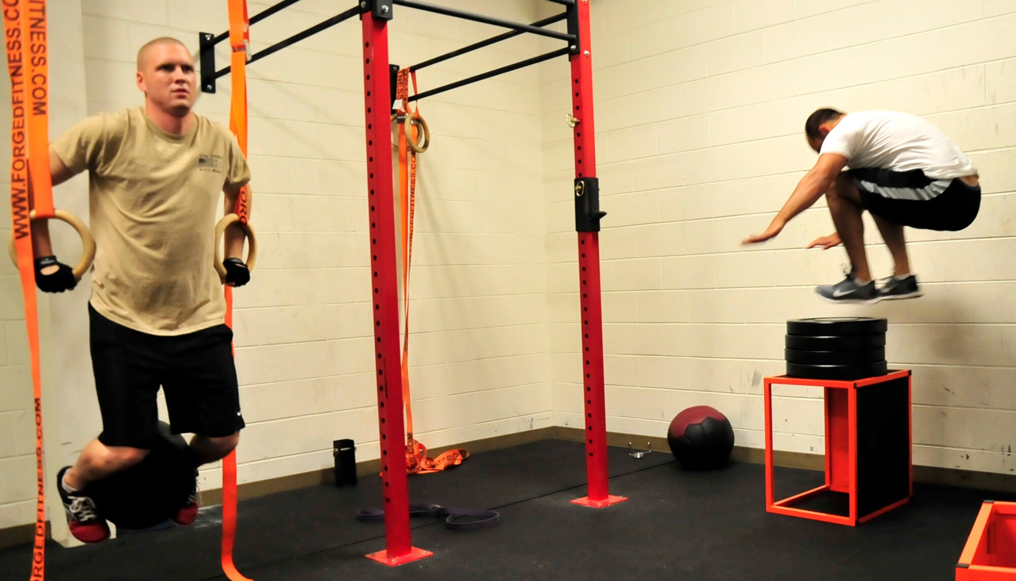 Staff Sgt. Shane Hilts, 436th Contracting Squadron contract specialist, does dips on gymnastics rings while 1st. Lt. Bruce Bentley, 436th CONS, jumps on weights Sept. 18, 2013, in the Xtreme Fitness Room at the Fitness Center on Dover Air Force Base, Del. Hilts and Bentley have been leading functional training workouts since the Xtreme Fitness Room opened on May 1. (U.S. Air Force photo/Tech. Sgt. Chuck Walker)