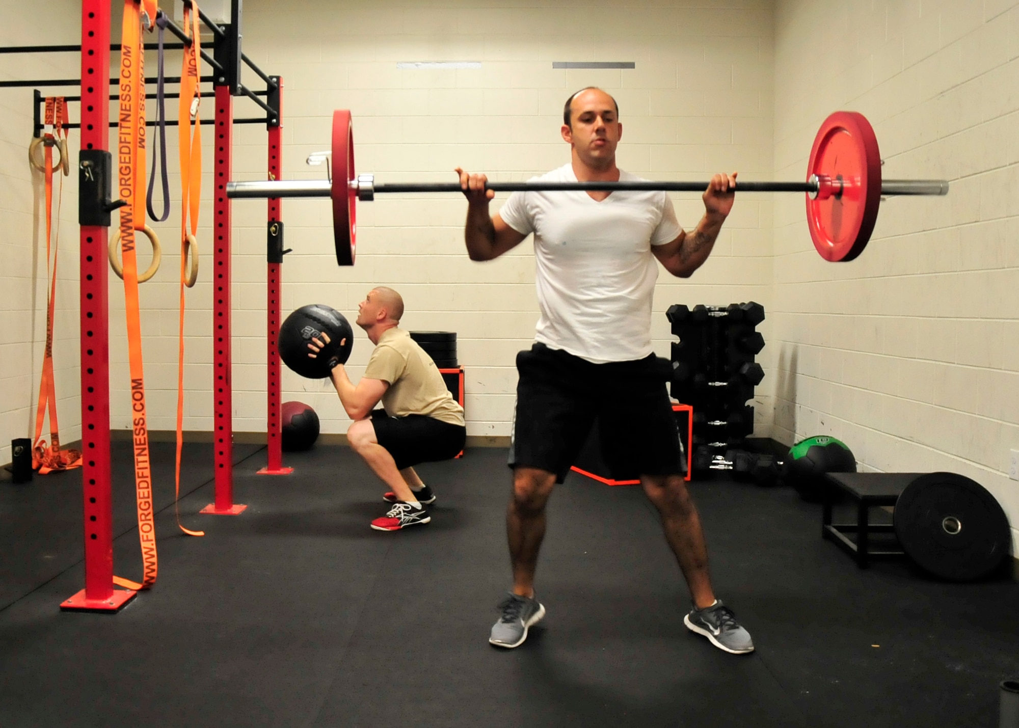 1st Lt. Bruce Bentley, 436th Contracting Squadron Officer In Charge Base Infrastructure flight, lifts weights as Staff Sgt. Shane Hilts works with a medicine ball Sept. 18, 2013, in the Xtreme Fitness Room at the Fitness Center on Dover Air Force Base, Del. The Xtreme Fitness Room opened on May 1, and recently expanded to 1,300 square feet on Sept. 1. (U.S. Air Force photo/Tech. Sgt. Chuck Walker)