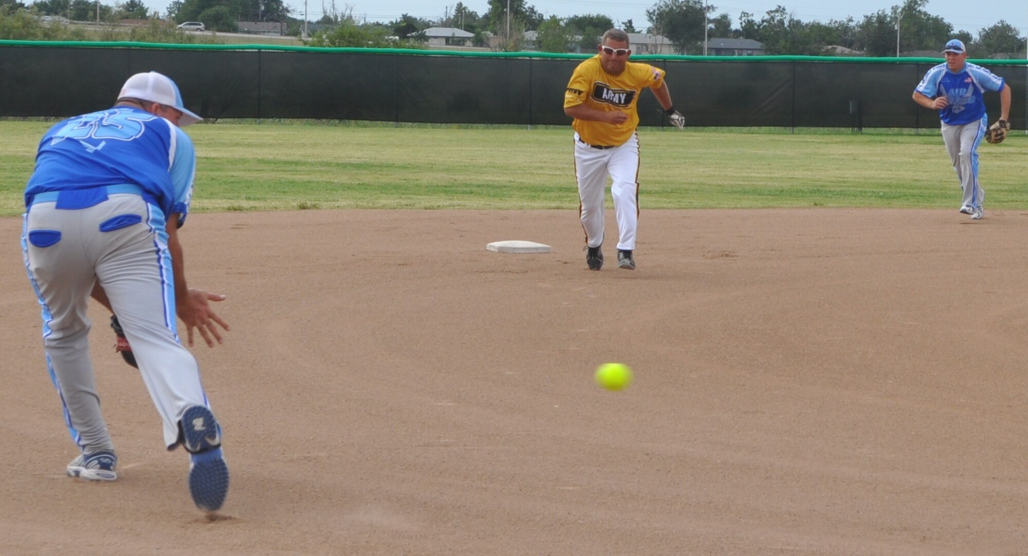 Air Force third baseman Christopher Blast lowers his glove to scoop up a grounder, and second baseman Joseph Dufault races to cover the bag, as Army pitcher Eric Querry heads for third. (Air Force photo by Mike W. Ray)