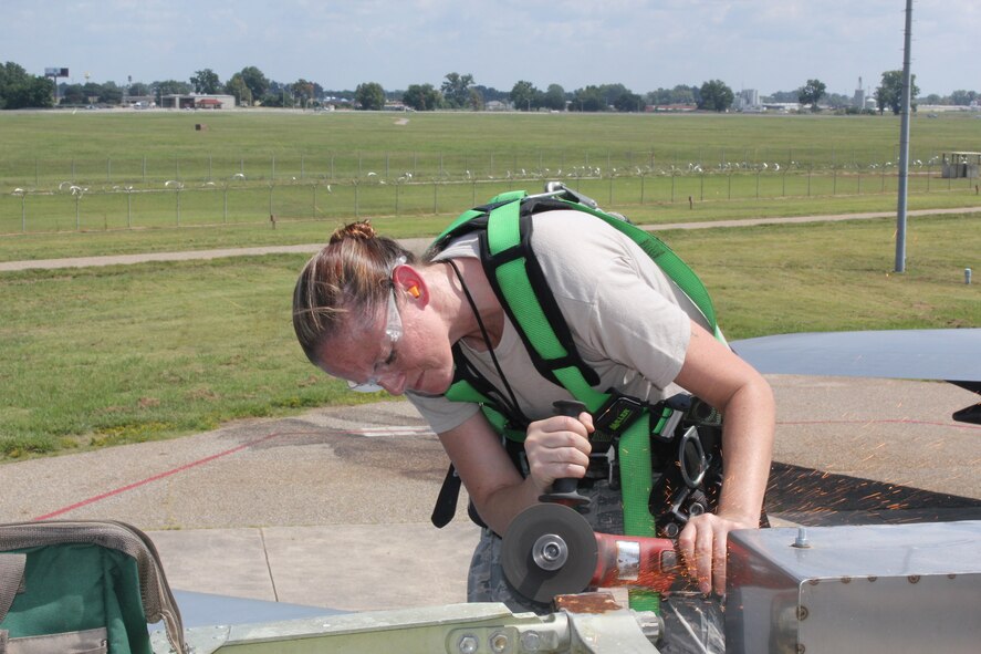 Staff Sgt. Elizabeth Germain, 2nd Maintenance Squadron metals technology journeyman, grinds a mounting lug on the flightline at Barksdale Air Force Base, La., Aug. 19, 2013. Pieces from the vertical fin mounting lugs were removed turning the  B-52H Stratofortress into a New Strategic Arms Reduction Treaty compliant ground instructional training aircraft. (U.S. Air Force photo/courtesy photo)