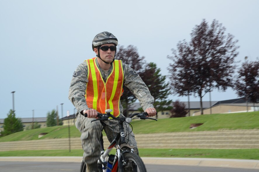 Staff Sgt. R.J. Biermann, 341st Missile Wing Public Affairs NCO in charge, wears proper personal protective equipment while riding a bicycle at Malmstrom Air Force Base on Sept. 17. Effective Sept. 12, all bicyclists on an Air Force installation must wear a highly visible outer garment during the day and outer garment containing retro-reflective materials at night, according to Air Force Instruction 91-207. The 341st MW Safety Office recommends all Airmen riding bicycles in uniform wear a vest, such as the one shown.  For those not in uniform riding bicycles on the base, the same type vest or a similar highly visible outer garment must be worn.  Reflective belts do not suffice as a highly visible outer garment by themselves, but may be used to add visibility and supplement required garments. (U.S. Air Force photo/Airman 1st Class Collin Schmidt)