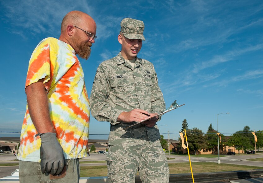 Airman 1st Class Shane Swick, 28th Contracting Squadron contract administrator, assists David Dirks, Midwest Roofing, LLC. roofer, in completing a labor check form at Ellsworth Air Force Base, S.D., Sept. 13, 2013. Swick works closely with contractors to ensure they are paid promptly and accurately and accomplish all work according to the established contractor. (U.S. Air Force photo by Airman 1st Class Alystria Maurer/Released)