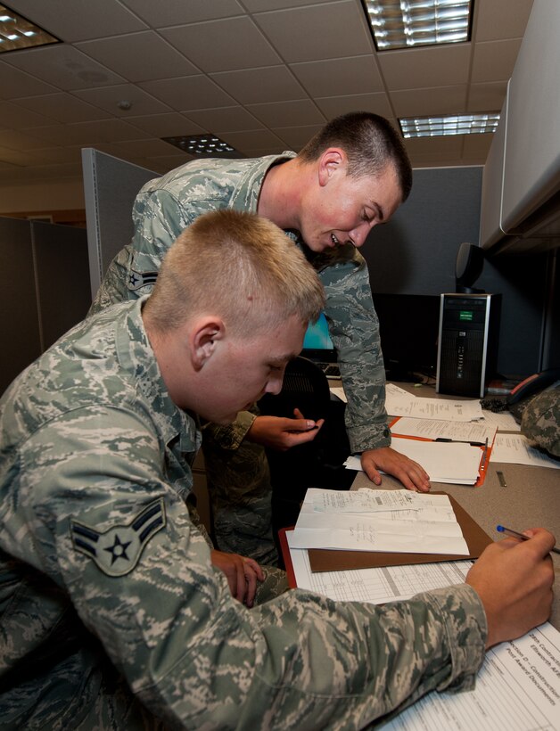 Airman 1st Class Kalvin Schultz, 28th Contracting Squadron contract officer, assists Airman 1st Class Shane Swick, 28th CONS contract administrator, with organizing a government purchase card binder at Ellsworth Air Force Base, S.D., Sept. 3, 2013. Airmen from 28th CONS are responsible for purchasing services, commodities and working contracts in order to keep base facilities operational. (U.S. Air Force photo by Airman 1st Class Alystria Maurer/Released)