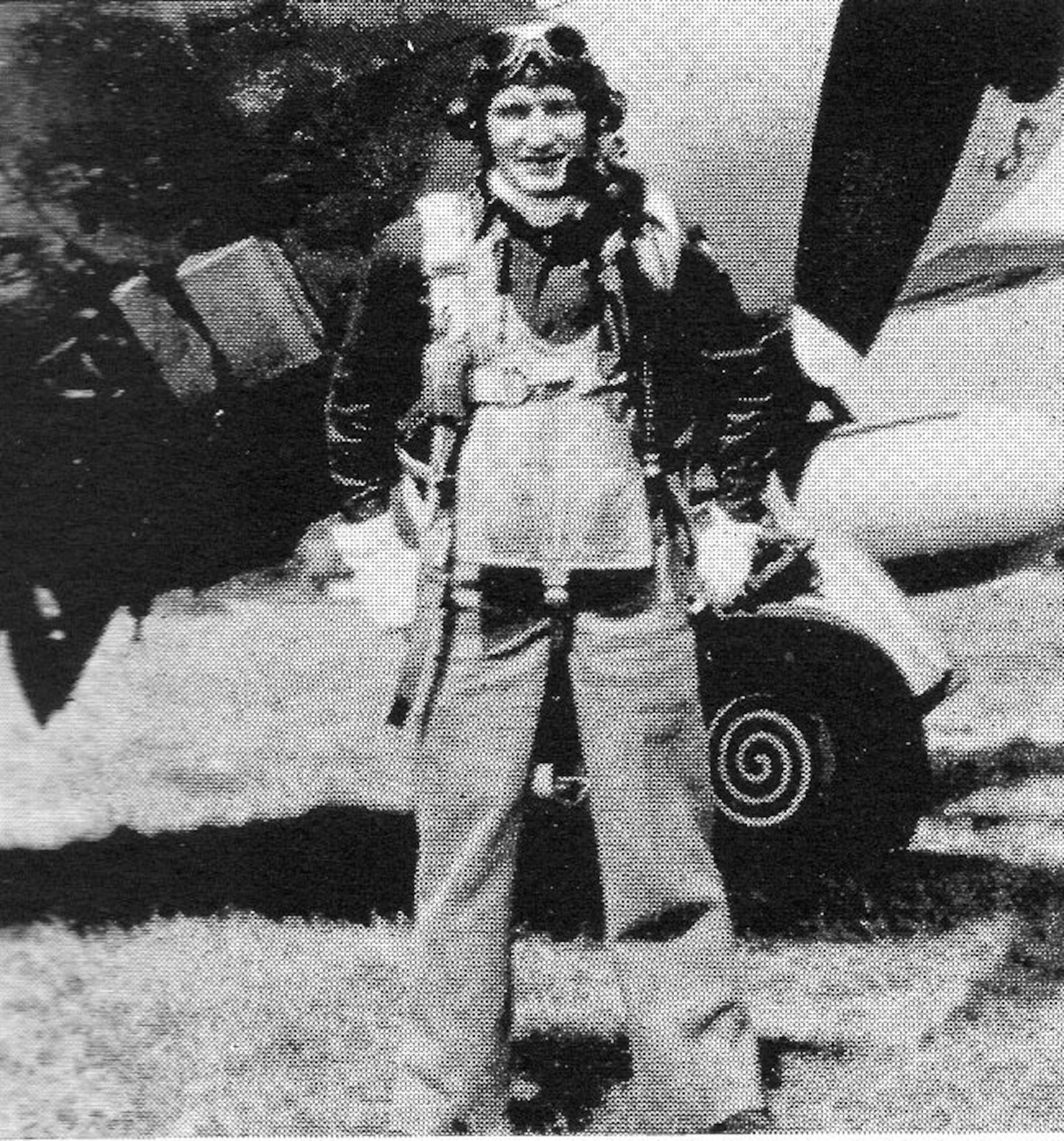 Capt. Uno A. Salmi, 406th Fighter Squadron, smiled for the camera in his flying gear next to a P-47 Thunderbolt.  He was one of the 406th senior pilots who conducted experimental takeoffs on a new advanced landing ground-style runway in England before the unit deployed forward to France.  Two takeoffs were safely made, each with a belly tank and two bombs; two 240-lb bombs the first time and two 500-lb bombs the second time, to make sure the new surface was safe for the group’s flight operations.  He went MIA on 16 June 1944.