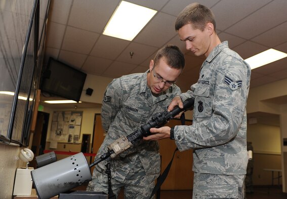Staff Sgt. Dylan Johnson, 5th Security Forces Squadron assistant armory non-commissioned officer in charge, observes weapon clearing techniques performed Senior Airman Preston Petersen, 5th SFS armorer during a visit from Chief Master Sgt. Dave Nordel, Twentieth Air Force command chief at Minot Air Force Base, N.D., Sept. 16, 2013. Safety is paramount during any situation involving weapons systems and proper checks are performed at each stage of their issue to negate the possibility of injury. (U.S. Air Force photo/Senior Airman Stephanie Sauberan)