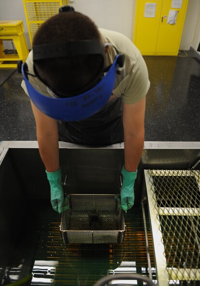 Airman 1st Class Kale McSpadden, 2nd Maintenance Squadron non-destructive inspection apprentice, dips an aircraft part into a fluorescent penetrant on Barksdale Air Force Base, La., Sept. 19, 2013. This process checks for cracks and other structural damage on the surface of an aircraft part or piece of equipment. The fluorescent penetrant seeps into the defect and takes around 30 minutes to completely identify it. (U.S. Air Force photo/Senior Airman Benjamin Gonsier)