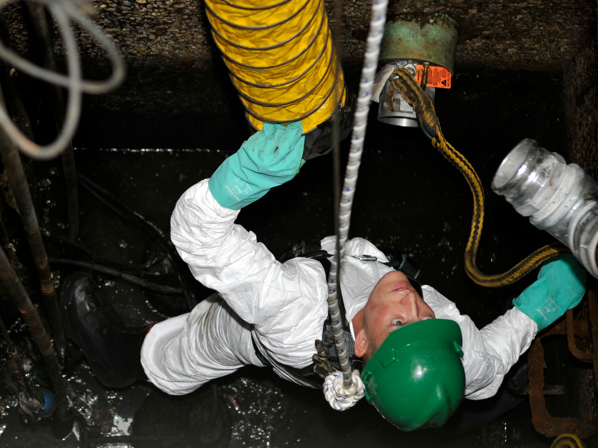 Airman 1st Class Jefferson Bowler, 2nd Civil Engineer Squadron water and fuel system maintenance apprentice, waits for a plastic hose to be lowered to him so he can install part of a bypass system, which allows base plumbing to remain uninterrupted during lift-station maintenance on Barksdale Air Force Base, Sept. 17, 2013. Once the hoses are connected, a new lift station will be installed and the bypass system will be removed. (U.S. Air Force photo/Airman 1st Class Benjamin Raughton)