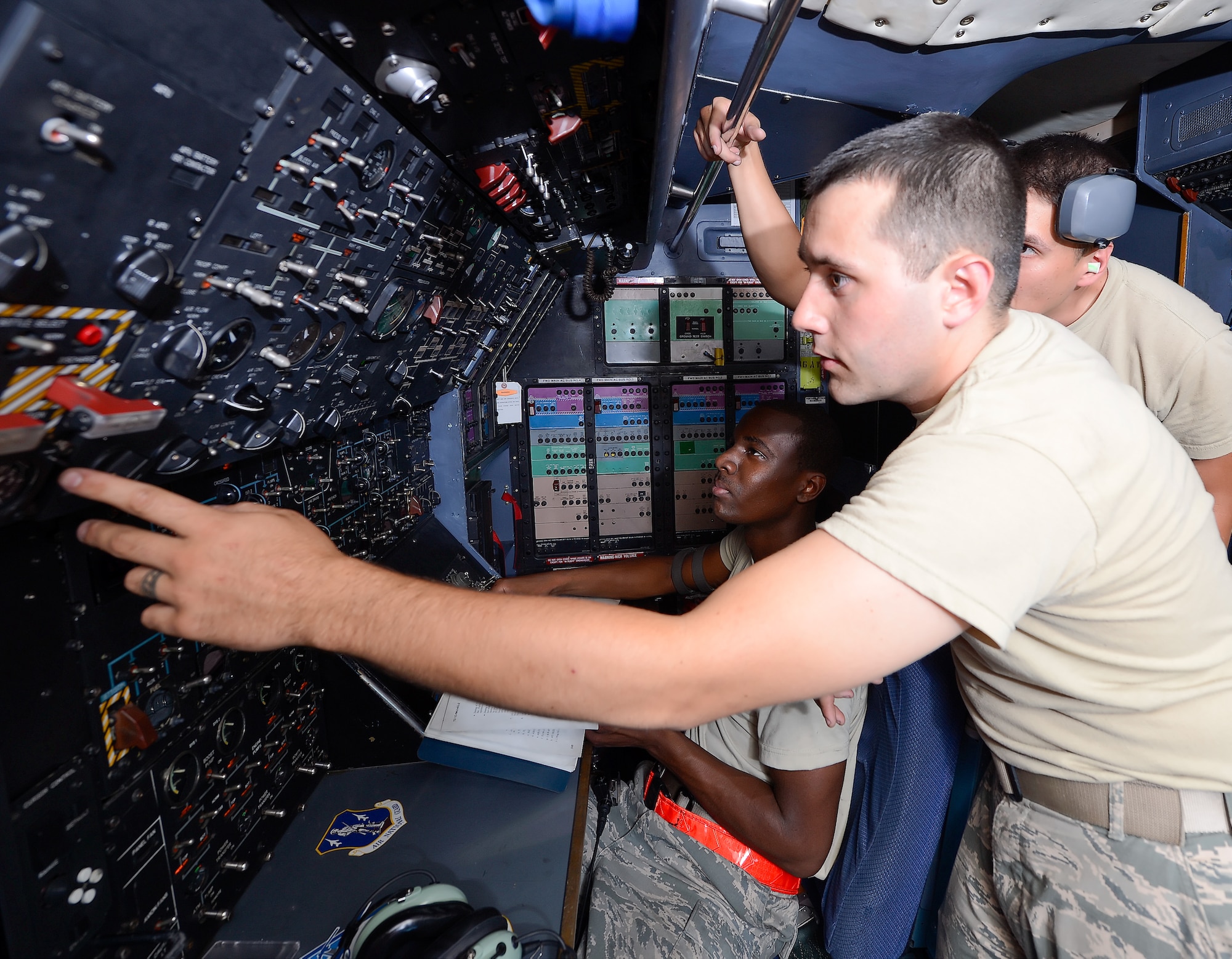 Airmen troubleshoot problems with a C-5M Super Galaxy from the flight engineers' station aboard the jet on Sept. 19, 2013 at Dover Air Force Base, Del. Shown are: Airman 1st Class Jacob Roose, foreground flipping switches, A1C Terry Thompson, seated with checklist, and Staff Sgt. Michael Mills who is monitoring the gauges. All airmen are with the 436th Aircraft Maintnenace Squdron. (U.S. Air Force photo/Greg L. Davis)