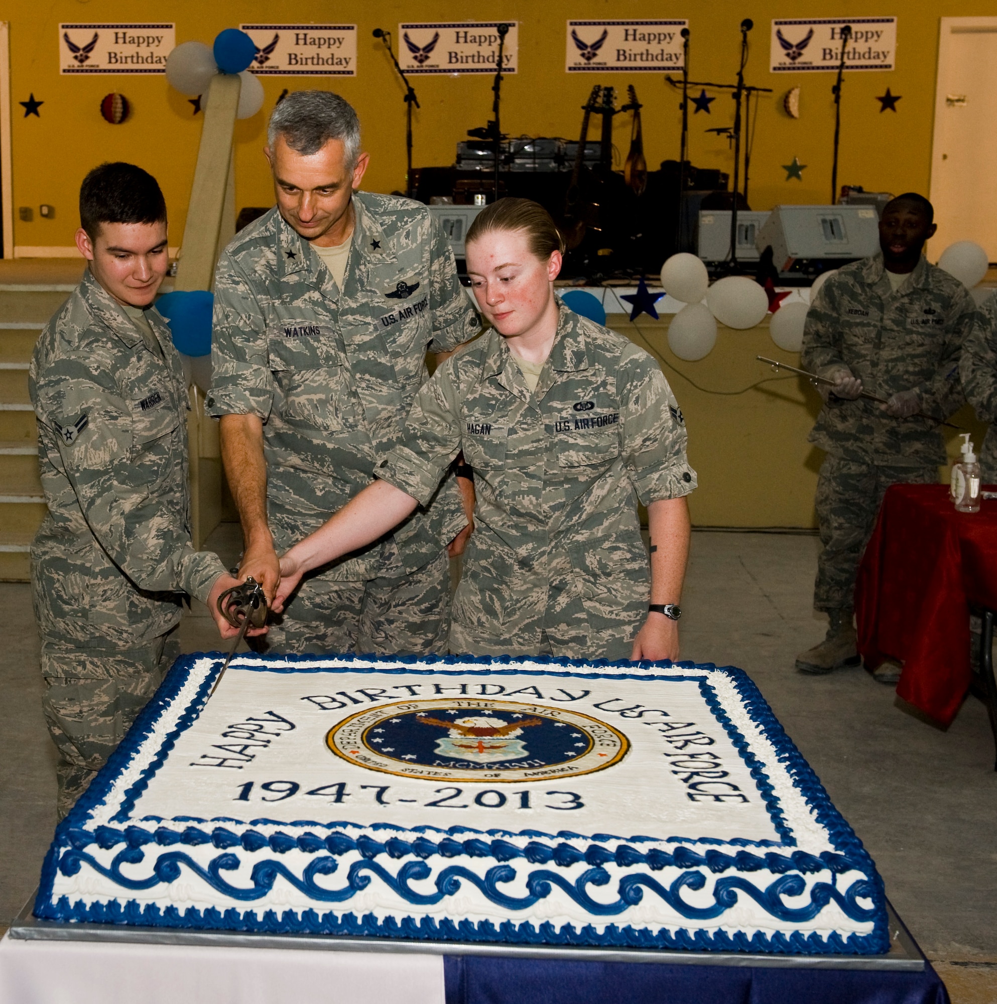 Brig. Gen. Roger Watkins along with Airmen 1st Class Katherine Hagan and Jacob Warren slice the cake during the Air Force birthday celebration at the 379th Air Expeditionary Wing in Southwest Asia, Sept. 18, 2013.Watkins is the 379th AEW commander. Hagan and Warren are both 71st Expeditionary Air Control Squadron surveillance technicians deployed from Spangdahlem Air Base, Germany. (U.S. Air Force photo/Staff Sgt. Benjamin W. Stratton)