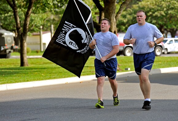 U.S. Air Force Staff Sgt. Justin Walter and Tech. Sgt. Kristopher Parker, 35th Civil Engineer Squadron explosive ordnance disposal technicians, run in commemoration of Prisoners of War and those Missing in Action at Misawa Air Base, Japan, Sept. 20, 2013. The POW/MIA flag was carried around the base during a 24-hour run to pay respect to those who have been captured or have gone missing in action. (U.S. Air Force photo by Airman 1st Class Zachary Kee) 