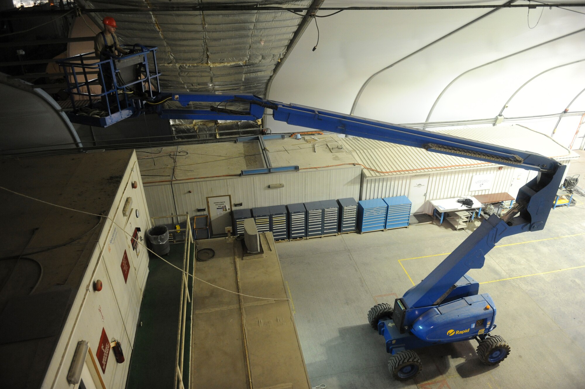 An Airman from the 577th Expeditionary PRIME BEEF Squadron, positions a lift to help install insulation during a hangar renovation at an undisclosed location in Southwest Asia, Sept 2, 2013. The hangar is being renovated due to wear and tear from the elements. (U.S. Air Force photos by Staff Sgt. Joshua J. Garcia)