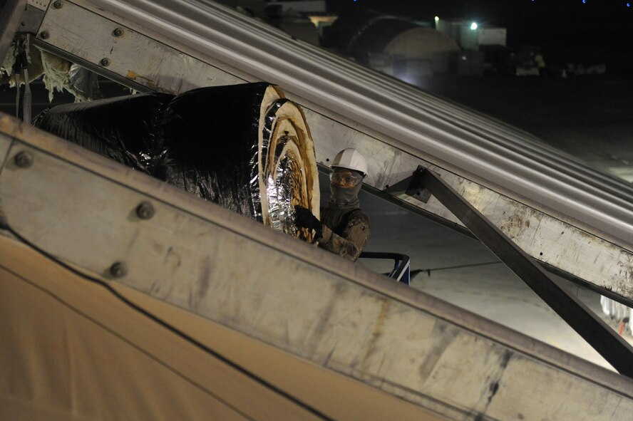 U.S. Air Force Senior Airman Derek Jones, 577th Expeditionary PRIME BEEF Squadron, moves insulation during a hangar renovation at undisclosed location in Southwest Asia August 29, 2013. The insulation will help the hangar keep a comfortable temperature for its occupants by reducing any unwanted heat loss or gain. The hangar is being renovated due to wear and tear from wind, sand and heat in the local area. Jones is native to Waverly, Va., and is deployed from Kadena Air Base, Japan (U.S. Air Force photo by Staff Sgt. Joshua J. Garcia)