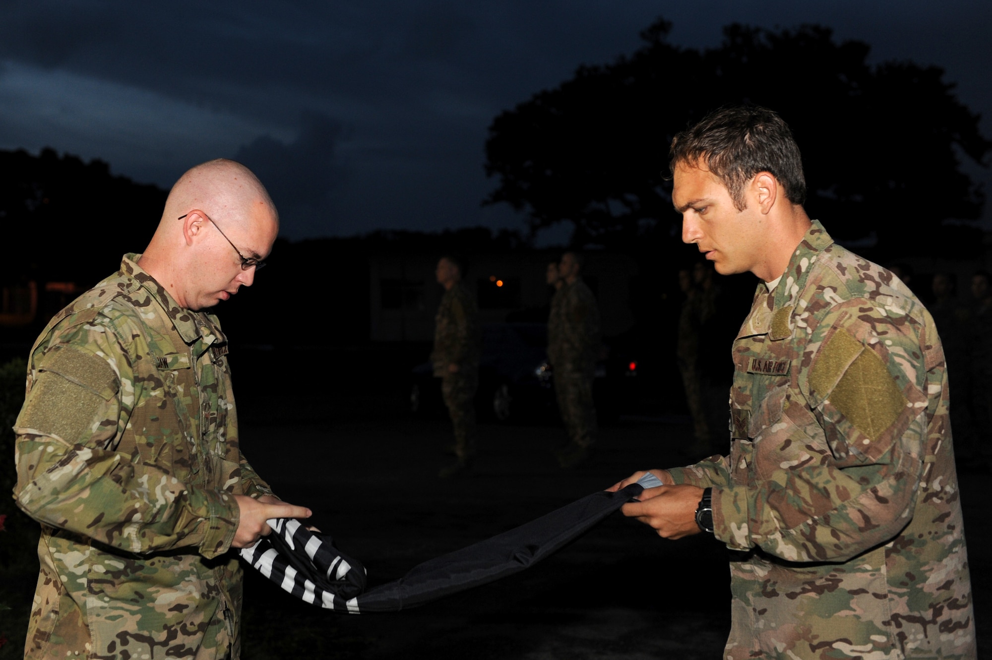 U.S. Air Force Senior Airman Jonathan Daw, 320th Special Tactic Squadron intelligence analyst, and Staff Sgt. Aaron Davis, 320th STS combat controller, fold the POW/MIA flag during the 24-hour vigil run at Marek Park on Kadena Air Base, Japan, Sept. 20, 2013. This is an annual event to honor more than 70,000 POW and MIA personnel. (U.S. Air Force photo by Airman 1st Class Hailey R. Davis)