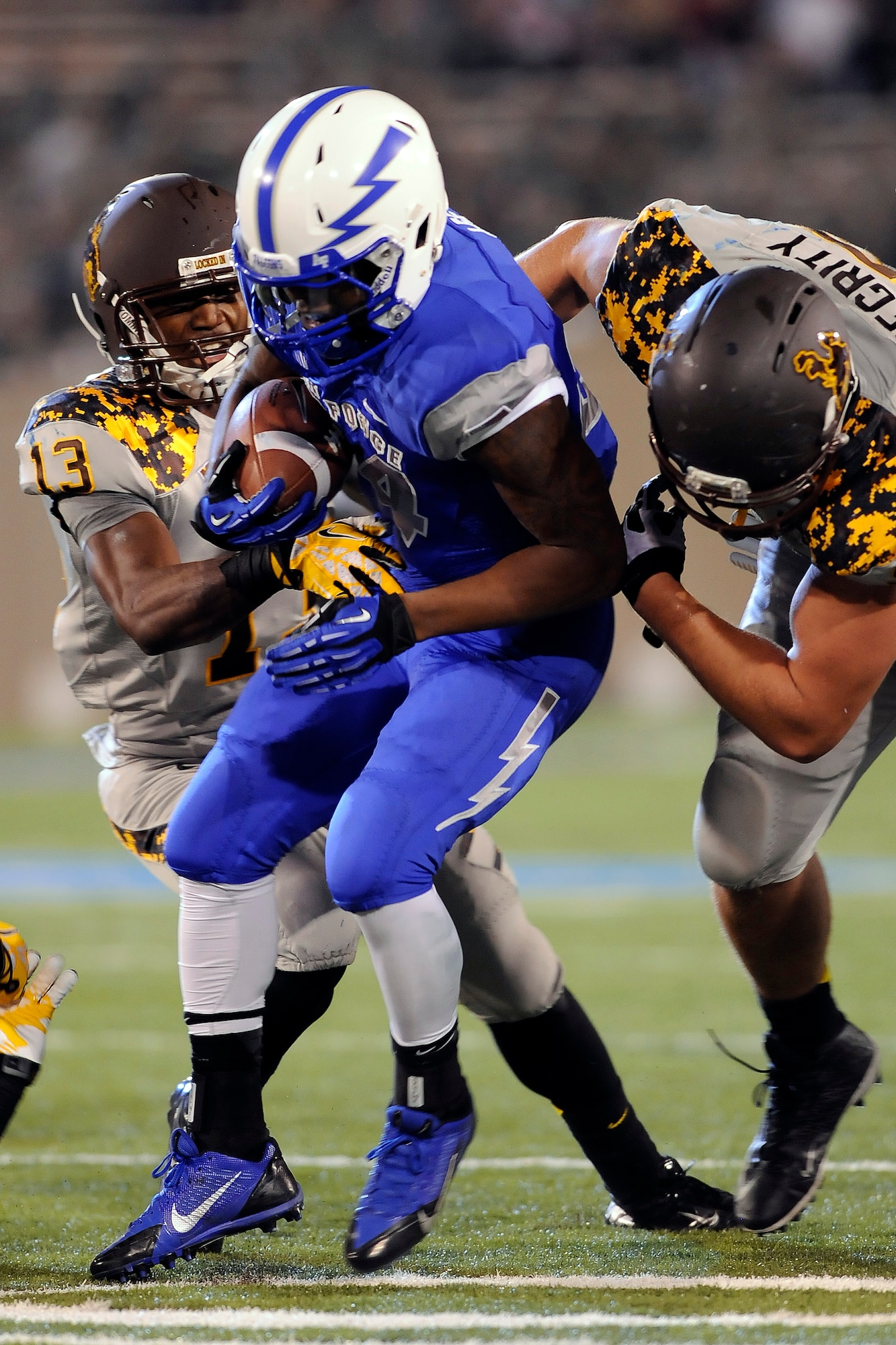 Junior running back Jon Lee gets wrapped up by two Wyoming defenders during the Air Force-Wyoming game at Falcon Stadium Sept. 21, 2013. Lee had eight carries for 82 yards in the Falcons' 56-23 loss to the Cowboys. (U.S. Air Force photo/Sarah Chambers)