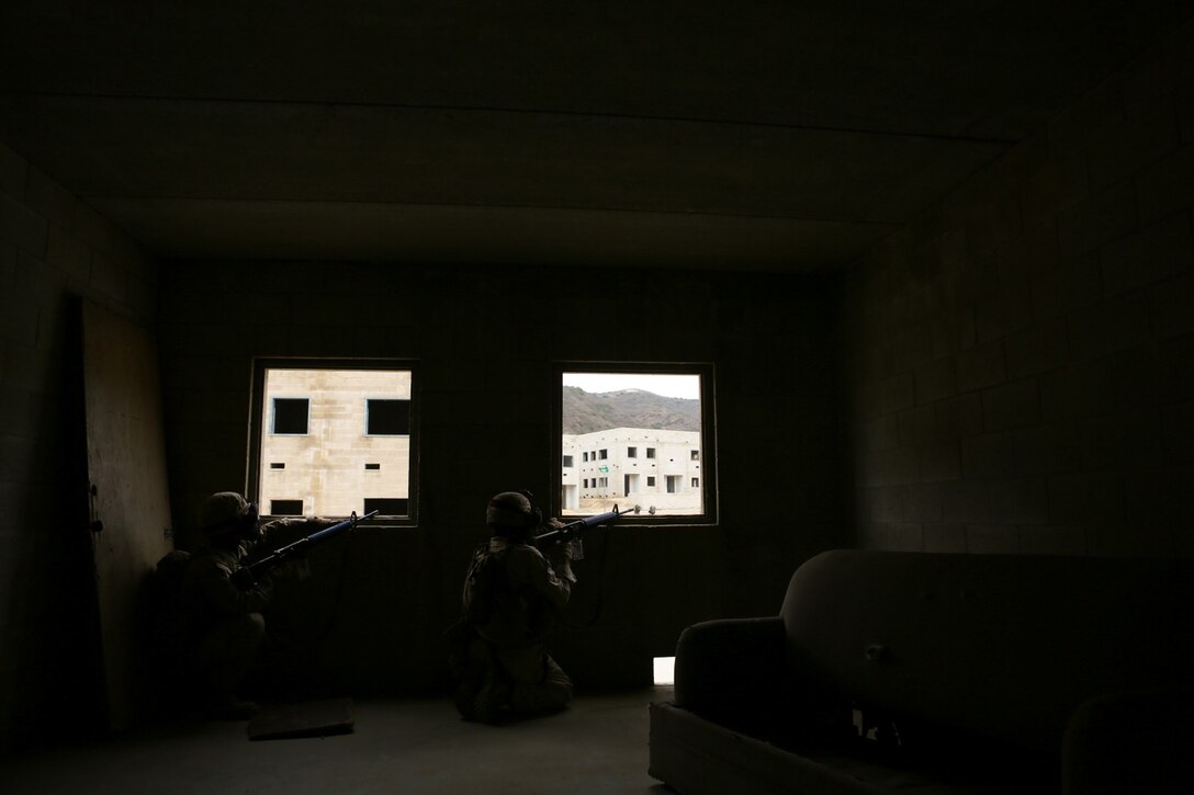 Riflemen with Delta Company, 1st Battalion, 1st Marine Regiment, keep a watchful eye out for enemy activity during an Urban Leaders Course training scenario at a military operations on urban terrain facility here, Sept. 19, 2013. The Marines provided around-the-clock security for a building at the facility and then assaulted a nearby building with armed role-players who were threatening overall security. The Marines, both friendly and enemy forces, used simunition rounds - simulated ammunition that contains paint for marking purposes. Delta Co. focused on laws of land warfare, urban warfare and counterinsurgency during the training.