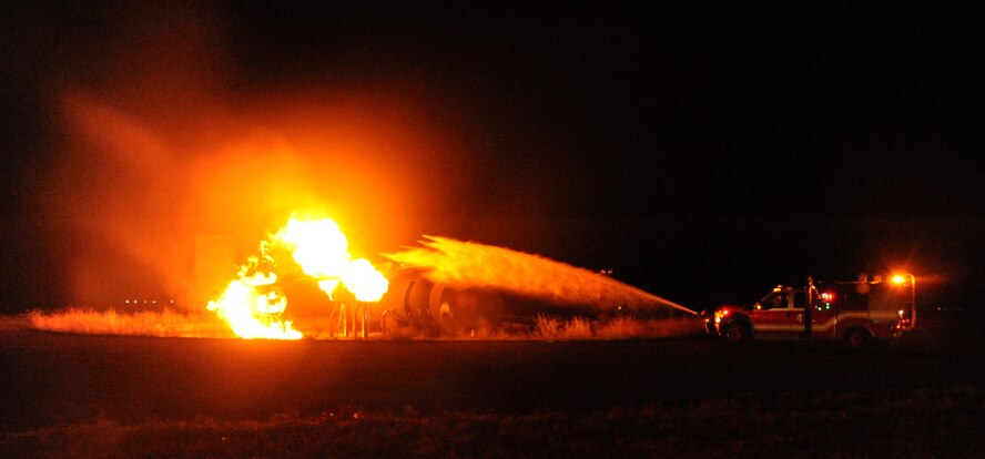 A fire truck from the 92nd Civil Engineering Squadron Fire Department sprays water at a fire at Fairchild Air Force Base, Wash., Sept. 16, 2013.  The mock scenario was for the benefit of Col. Brian Hill's immersion as Fairchild's vice commander.  (U.S. Air Force photo by Airman 1st Class Sam Fogleman/Released)