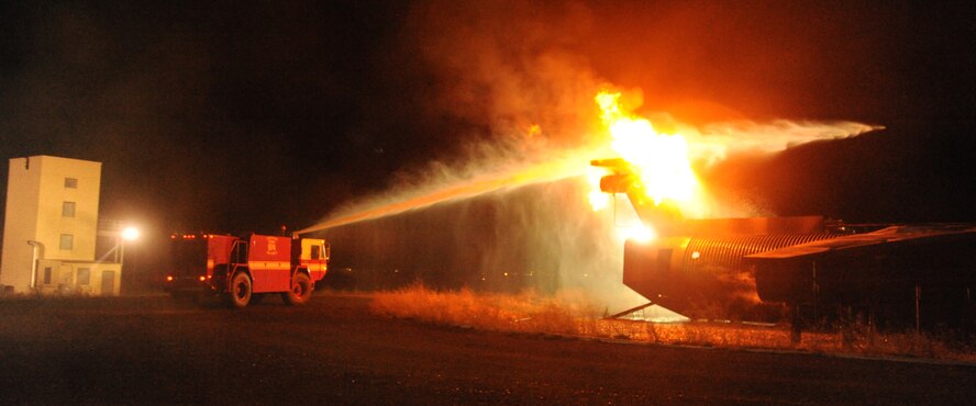 A fire engine from the 92nd Civil Engineering Squadron Fire Department propels water toward flames at Fairchild Air Force Base, Wash., Sept. 16, 2013.  The scenario was included in Col. Brian Hill's immersion as vice commander of the base.  (U.S. Air Force photo by Airman 1st Class Sam Fogleman/Released)
