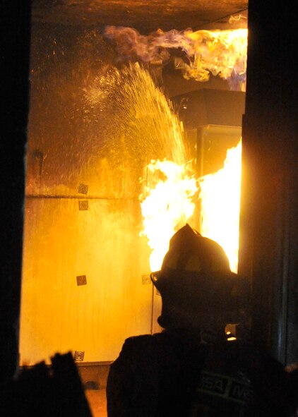 92nd Civil Engineer squadron firemen work to contain a live, simulated fire at Fairchild Air Force Base, Wash., Sept. 16, 2013. This training mission was conducted at night to better prepare them for any environment they may face. (U.S. Air Force photo by Senior Airman Mary O'Dell/Released)