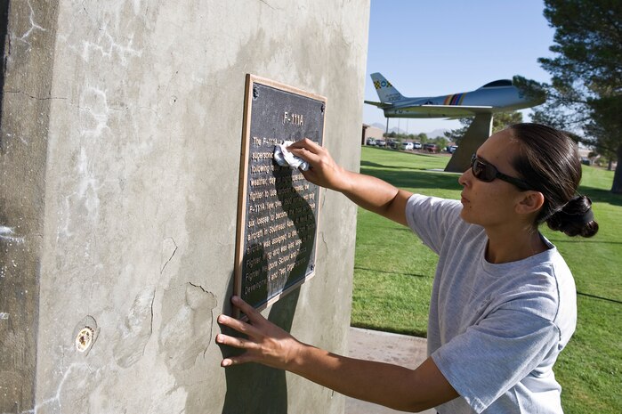 Staff Sgt. Elisa Guzman, 414th Combat Training Squadron weapons technician, cleans the plaque of an F-111A Aardvark static display at Freedom Park Sept. 18, 2013, at Nellis Air Force Base, Nev. Members from various units volunteer to clean the aircraft at Freedom Park at least once a year preserve the paint and plaques. (U.S. Air Force photo by Senior Airman Matthew Lancaster)