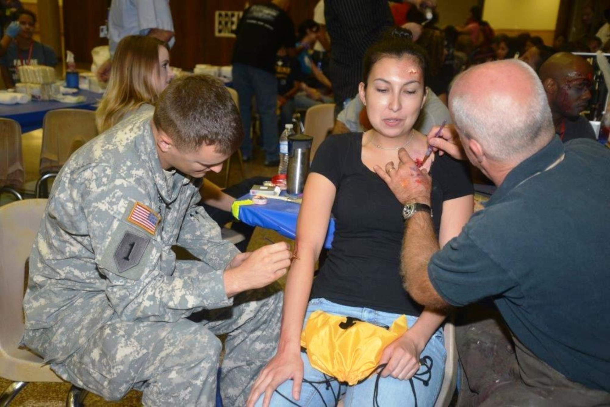 Army Sgt. David Shaffee, San Antonio Military Medical Center, Family and Community Medicine, assists Ken Lawsen, a city of Austin, Texas, paramedic supervisor apply moulage to nursing student, Valerie Rios at the Alzafar Shrine Temple, in San Antonio. Nursing students from seven medical schools from around the city of San Antonio, volunteered to become patients during the San Antonio Mass casualty Exercise Event, Sept. 19, 2013. The exercise was organized by Southwest Texas Regional Advisory Council or STRAC. (U.S. Air Force Photo/Senior Master Sgt. Minnie Jones)