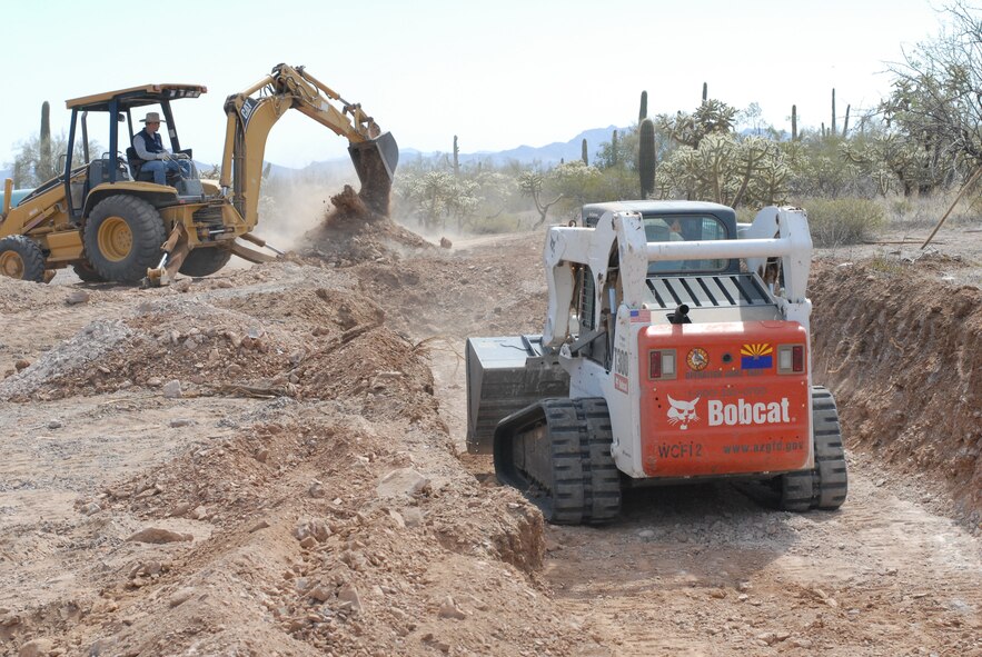 Artificial water catchments are constructed to provide water throughout the year for Sonoran Desert animals like Desert Bighorn and deer, and are also used by many other species of wildlife. Shown here, a crew excavates the ground in order to bury large underground water storage containers at the Barry M. Goldwater Range-East.