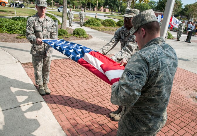 (Left to right) Airman 1st Class Matthew Lewis, Airman 1st Class Antwon Vaughn, and Senior Airman Tyler Vaughn, all members of the Joint Base Charleston Honor Guard fold the American flag during the Prisoner of War/Missing in Action retreat ceremony Sept. 23, 2013, at JB Charleston – Air Base, S.C. The ceremony included a 21-gun salute by the Honor Guard, a wreath-laying and bagpipe music in recognition of captured and missing U.S. servicemembers. (U.S. Air Force photo/Senior Airman Ashlee Galloway)
