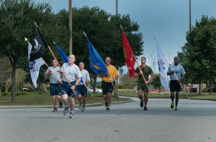 Members from each military branch run with their respective service flags to the Joint Base Charleston – Air Base parade grounds for the start of the Prisoner of War/Missing in Action Retreat ceremony Sept. 20, 2013, at JB Charleston, S.C. Teams from various joint base units took part in a vigil run around the base track, carrying the POW/MIA flag around the track non-stop for 24 hours.  (U.S. Air Force photo/Senior Airman Ashlee Galloway)