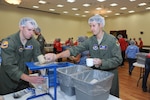 Capt. John Schwartz (left) and Capt. Chris Puccia, 99th Flying Squadron, fill bags of food for the “Feed My Starving Children” program at the Schertz Civic Center Sept. 20. Members of the 99th Flying Training Squadron volunteer at the center to package dried meals for malnourished children around the world. (U.S. Air Force photo by Rich McFadden/released)