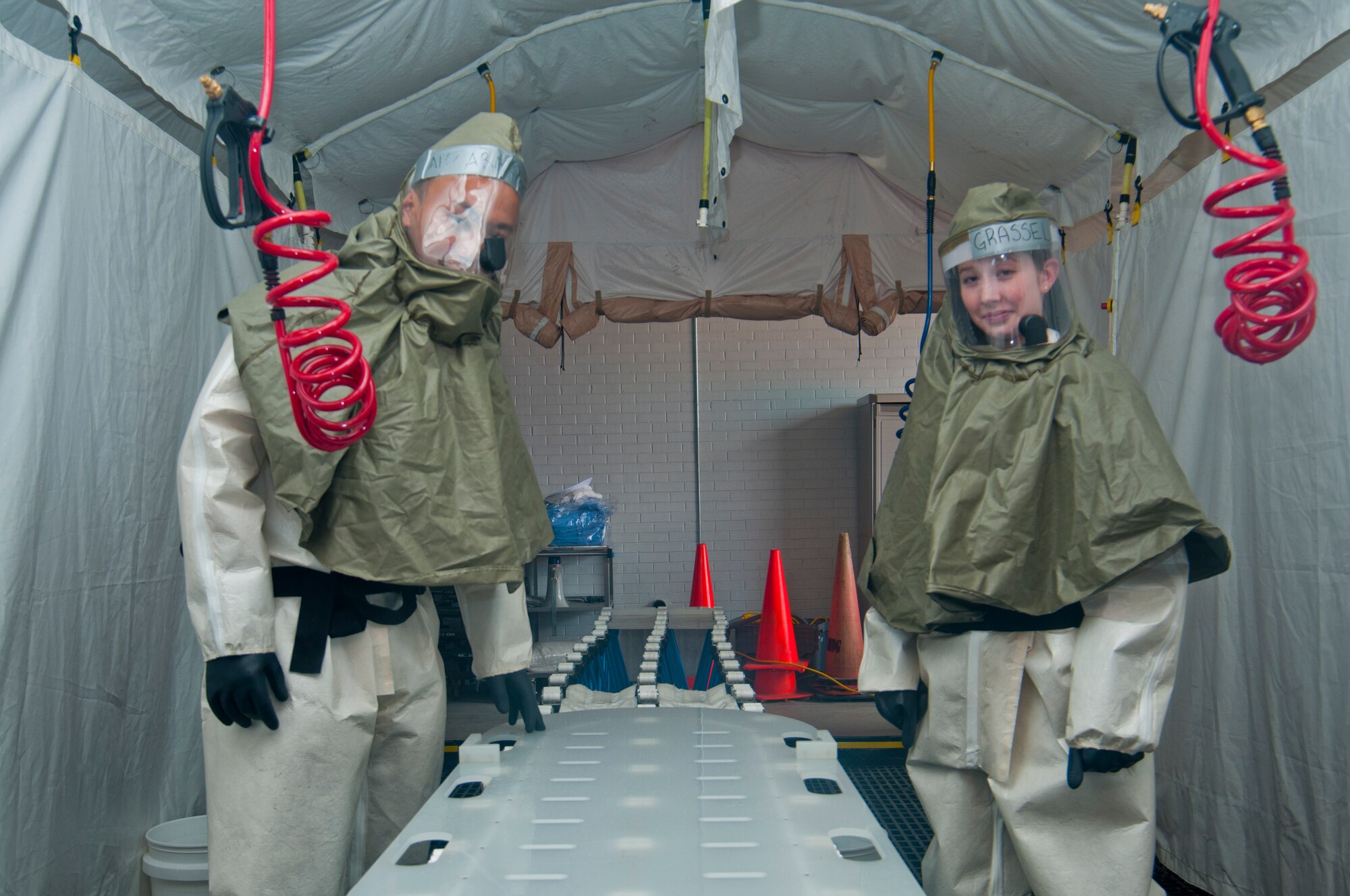 Senior Airman Romar Armamento, 90th Medical Operations Squadron Pediatrics medical technician, and Airman 1st Class Felicia Grassel, 90th Medical Group physical therapy technician, pose Sept. 19, 2013, in a decontamination shelter used to clean chemically contaminated patients. The suits the Airmen wear are training versions of real-world protective gear they would wear while working as part of the in-place patient decontamination team. (U.S. Air Force photo by Airman 1st Class Jason Wiese)