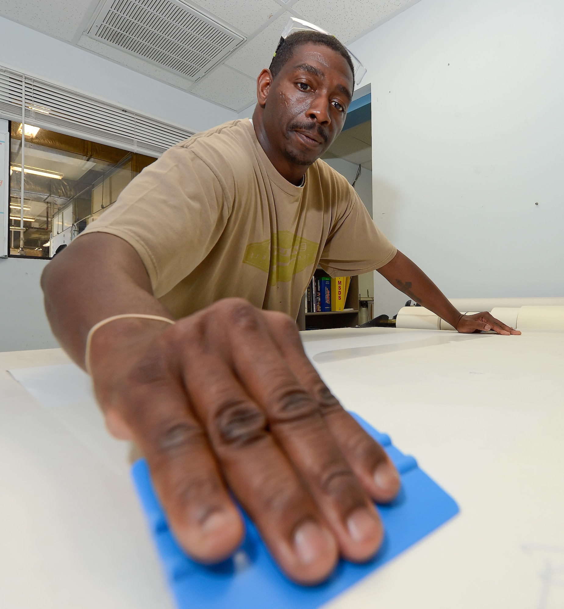 Antoine Robinson of the 436th Aircraft Maintenance Squadron corrosion control shop, presses down part of a decal to transfer paper on Sept. 4, 2013 at Dover Air Force Base, Del. The completed decal will be applied to a metal aircraft part to make a mask for important markings that must be permanent. (U.S. Air Force photo/Greg L. Davis)
