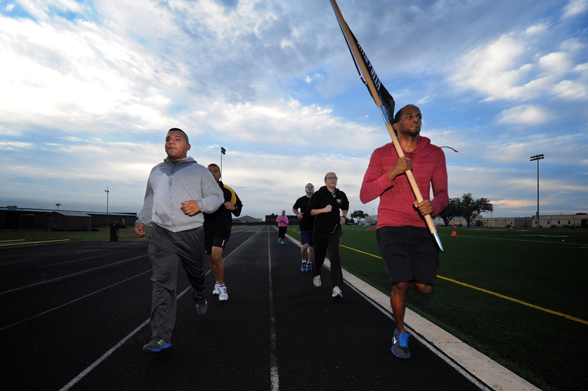 U.S. Air Force Airmen from the 27th Special Operations Comptroller Squadron carry the Prisoner of War/Missing in Action flag around the track during the 24-hour POW/MIA Vigil Run Sept. 20, 2013 at Cannon Air Force Base, N.M.  This event was held to honor and remember POW and MIA service members.  (U.S. Air Force photo/Senior Airman Jette Carr)