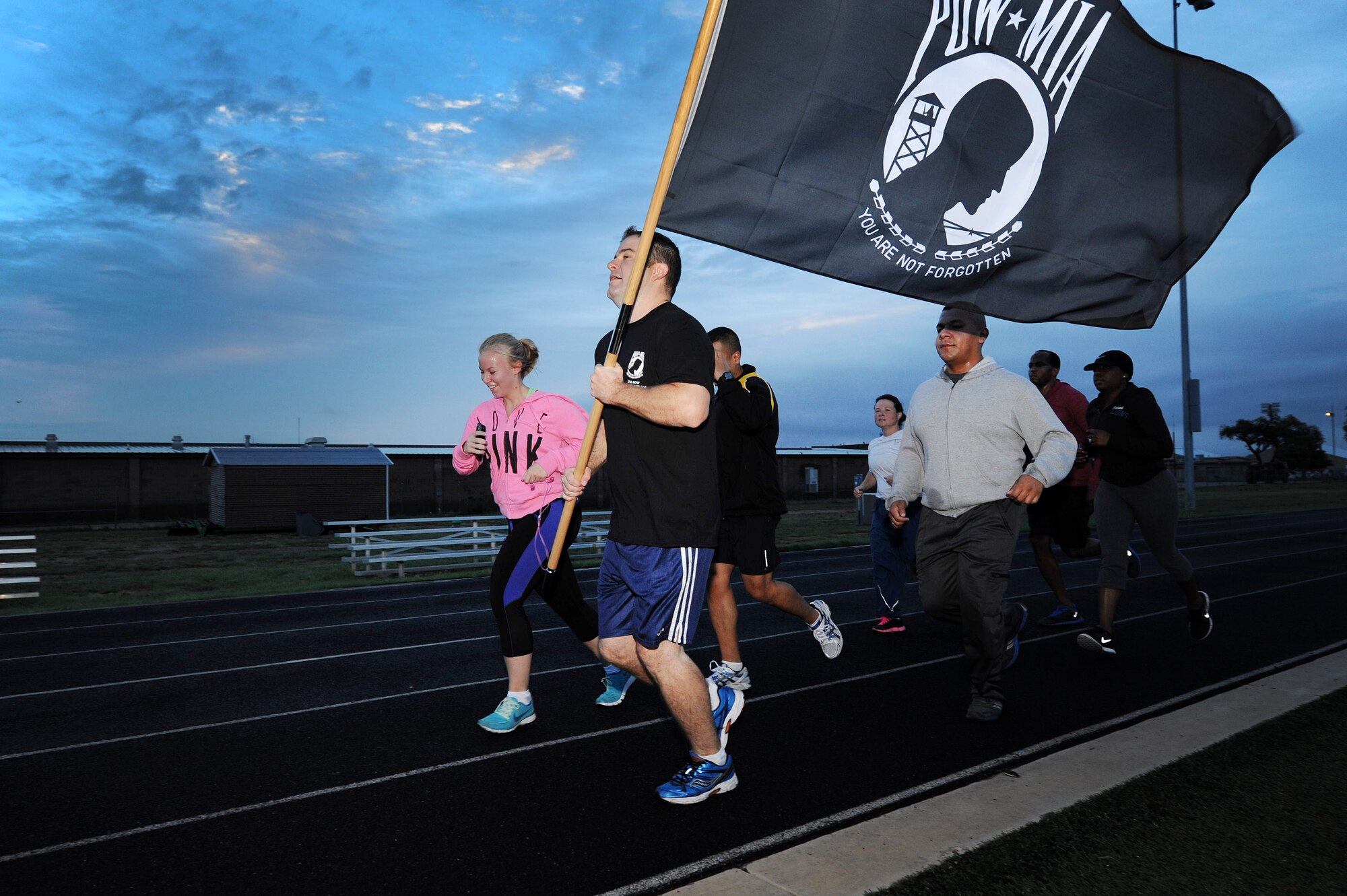 U.S. Air Force Airmen from the 27th Special Operations Comptroller Squadron carry the Prisoner of War/Missing in Action flag around the track during the 24-hour POW/MIA Vigil Run Sept. 20, 2013 at Cannon Air Force Base, N.M.  This event was held to honor and remember POW and MIA service members.  (U.S. Air Force photo/Senior Airman Jette Carr)