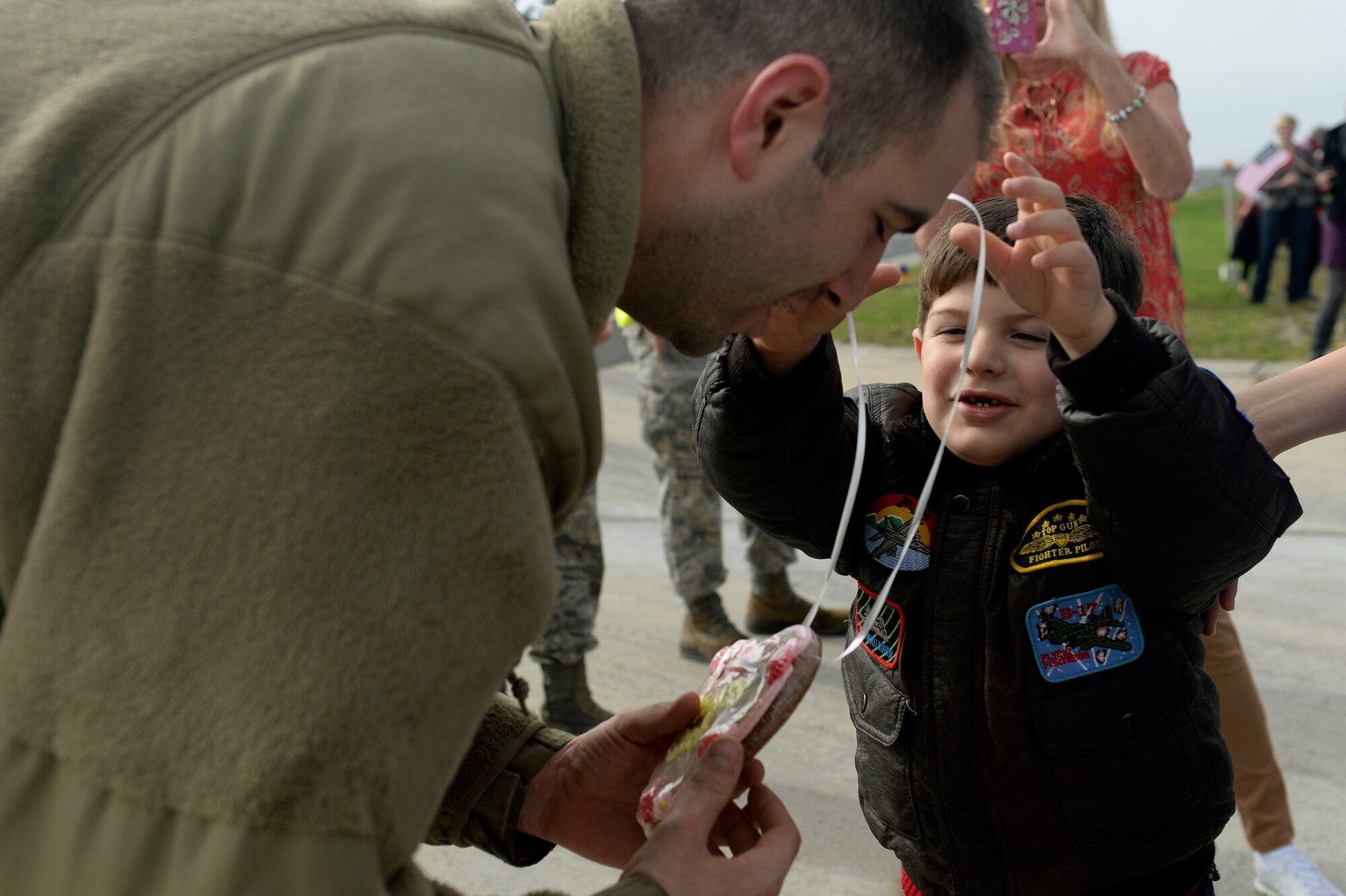 SPANGDAHLEM AIR BASE, Germany—Senior Airman Sean Capehart, a 52nd Equipment Maintenance Squadron aircraft structural maintenance journeyman, receives a gift from his son after returning home from a deployment Sept. 21, 2013, at Spangdahlem Air Base, Germany. Capehart and members of the 480th Fighter Squadron and supporting agencies deployed to support Operation Enduring Freedom. (U.S. Air Force photo by Senior Airman Rusty Frank/Released)
