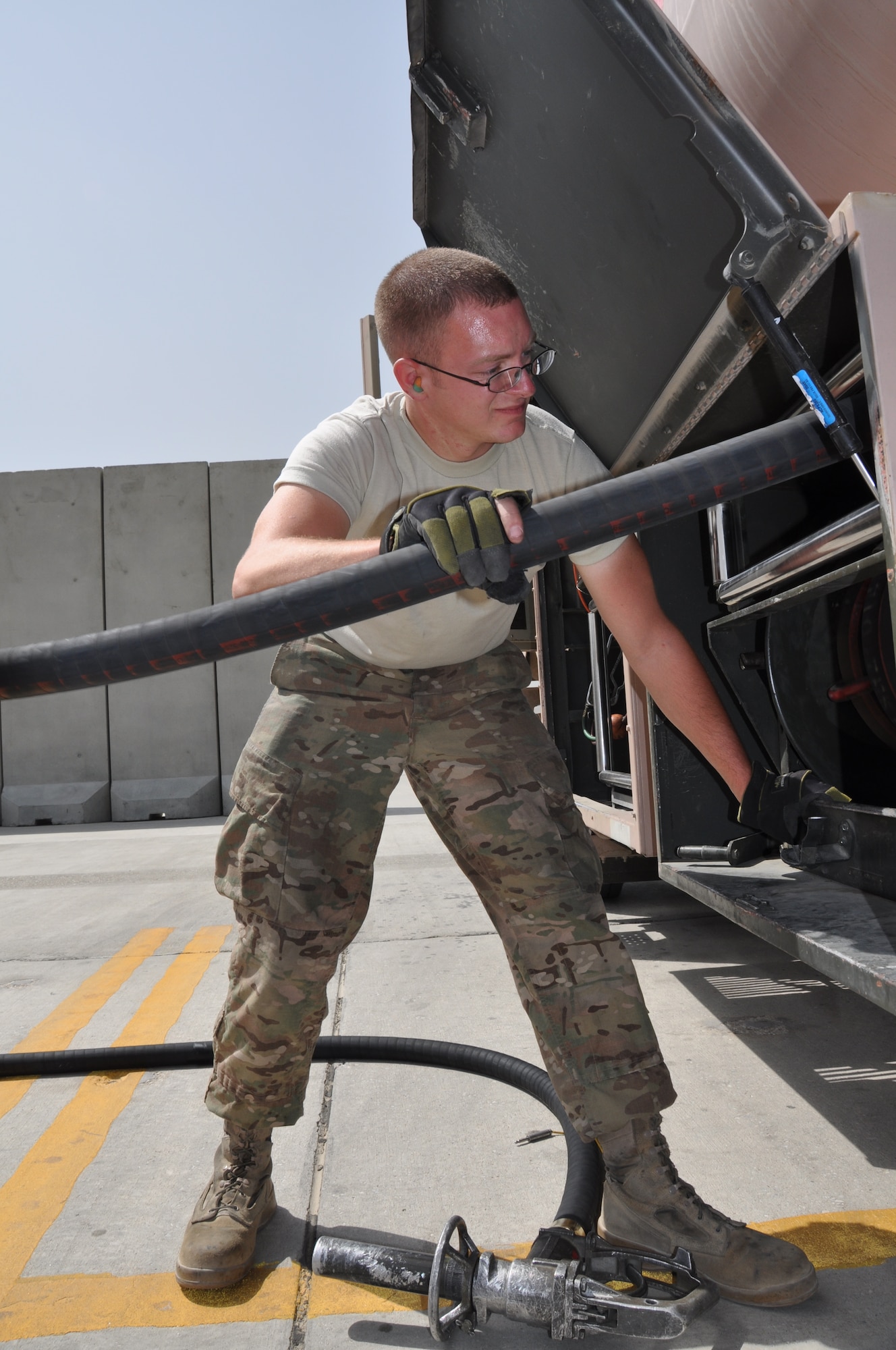 Senior Airman Robert Ellis, 455th Expeditionary Logistics Readiness Squadron refueling unit operator, deployed from Holloman Air Force Base, N.M., and a native of Gladstone, Mo., reels in the over-the-wing fuels servicing hose after refueling an aircraft at Bagram Airfield, Afghanistan, Sept. 18, 2013. (U.S. Air Force photo/Tech. Sgt. Rob Hazelett)