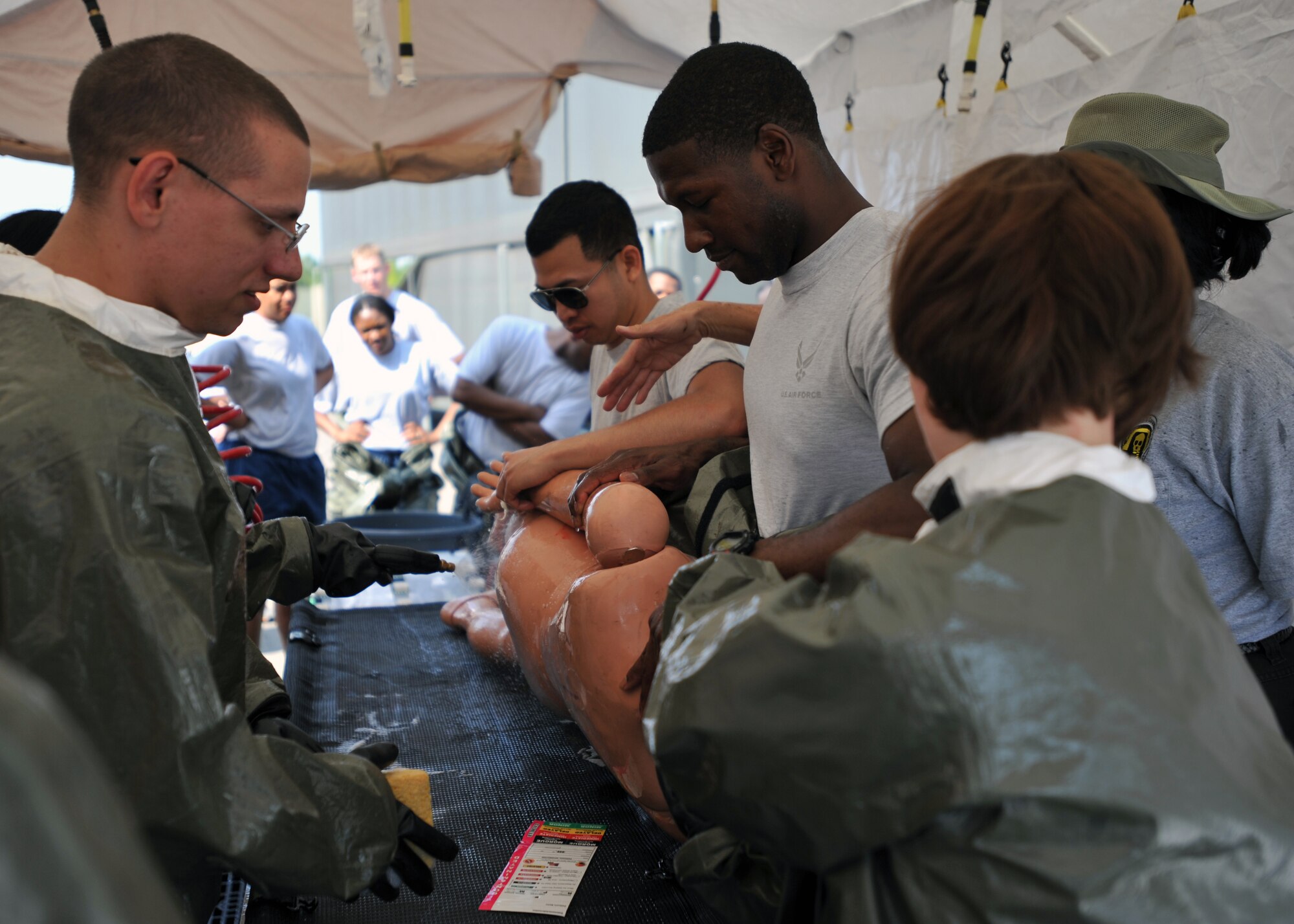 Members of the 51st Medical Group clean a training dummy during an in-place patient decontamination training course at Osan Air Base, Republic of Korea, Sept. 19, 2013. The 22 participants in the training course learned all of the necessary steps in processing decontaminated patients, as well as how to set up the pop-up decontamination facility. (U.S. Air Force photo/Senior Airman Siuta B. Ika)