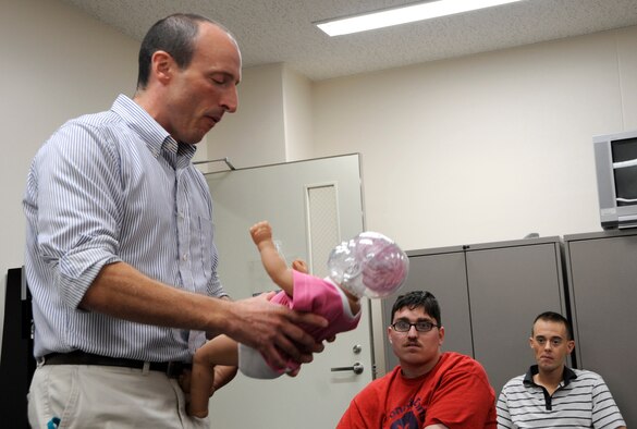 David Powell, 35th Medical Operations Squadron Family Advocacy Program outreach manager, uses a model infant to show the dangers of Shaken Baby Syndrome during the Dads 101 class at Misawa Air Base, Japan, Sept. 19, 2013. SBS is the name given to the collective symptoms of abuse resulting from the violent whiplash like movements when shaking a baby. The Dads 101 class has become mandatory for any male wanting to take paternity leave. For more information, contact your first sgt. or commander about the WEASEL NOTAM – 35FW-13-15 Paternity Leave and Family Enhancement. (U.S. Air Force photo by Airman 1st Class Kaleb Snay)