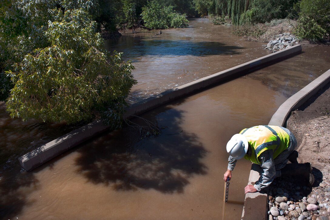U.S. Air Force Lt. Col. Tom Niichel measures the depths of flood waters along a bike path while conducting a site survey of bridges affected by flooding in Loveland, Colo., Sept. 19, 2013. Niichel is assigned to the Colorado Air National Guard's 240th Civil Engineering Flight.