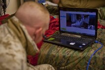Cpl. James Register, a Marine with Combat Logistics Regiment 2, Regional Command (Southwest), watches his computer screen at Camp Leatherneck, Helmand province, Afghanistan, during the delivery of his first child Sept. 18, 2013. Register watched the birth of his baby girl on a computer more than 7,000 miles away from home.