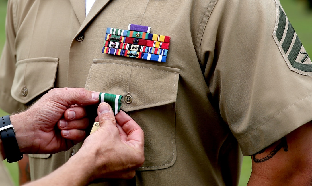 Staff Sgt. Charles E. Dishman receives the Navy and Marine Corps Commendation Medal, with combat distinguishing device, from Lt. Col. John C. Osborne, commanding officer of 2nd Combat Engineer Battalion, 2nd Marine Division, aboard Marine Corps Base Camp Lejeune Sept. 20, 2013. Dishman was deployed to Afghanistan in support of Operation Enduring Freedom from September 2012 to April 2013. During the deployment, he conducted more than 40 small-scale breaching missions and personally cleared 1,800 meters of improvised explosive device laden roads, while under enemy fire.