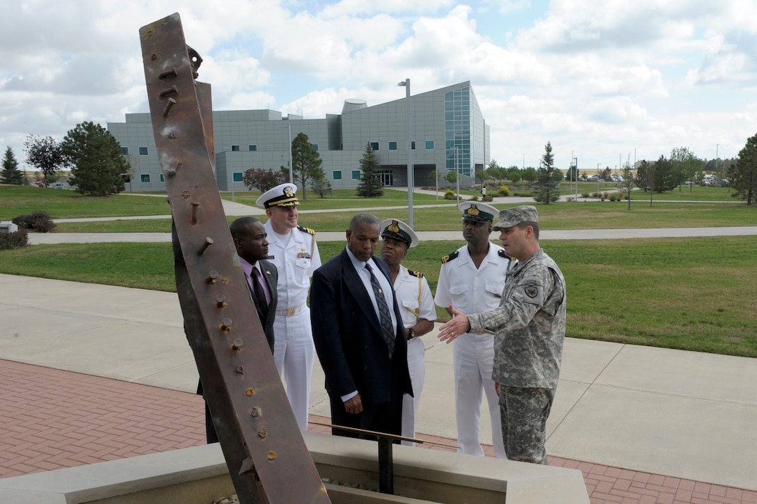 U.S. Army Brig. Gen. Robert Walters, NORAD and USNORTHCOM Intelligence Director points out the World Trade Center beam on display at the 9-11 Memorial in front of NORAD and USNORTHCOM headquarters at Peterson Air Force Base, Colo. to members of the Royal Bahamas Defence Force (RBDF) on Sep. 20. Pictured from left to right are RBDF Leading Seaman Julian Smith, Intelligence Officer; U.S. Navy Cmdr. Sam Wartell, the U.S. Defense Attaché, U.S. Embassy in The Bahamas; RBDF Cmdr. Michael Sweeting, Security Intelligence Officer; RBDF Lt. Origin Deleveaux, Jr., Aide-De-Camp to Commodore Roderick Bowe and RBDF Public Relations Officer; Lt. Shawn Adderley, RBDF Legal Affairs Officer; and Brig. Gen. Walters.