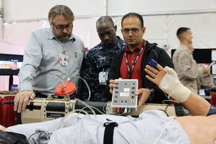 Mark Urrutic (right) of Combat Support Systems Family of Field Medical Equipment shows Dwayne Hill and Petty Officer 1st Class Jacob Kabbah the portable patient transport life support system during the Modern Day Marine Expo Sept. 24 at Marine Corps Base Quantico, Va. At the expo, Marines can see the gear Marine Corps Systems Command program offices are fielding and will field in the future. 