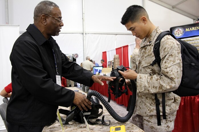 Don Holman of Infantry Weapons Systems describes the Joint Service General Purpose Mask to Cpl. Charlie Nguyen during the Modern Day Marine Expo Sept. 24 at Marine Corps Base Quantico, Va. At the expo, Marines can see the gear Marine Corps Systems Command program offices are fielding and will field in the future. 