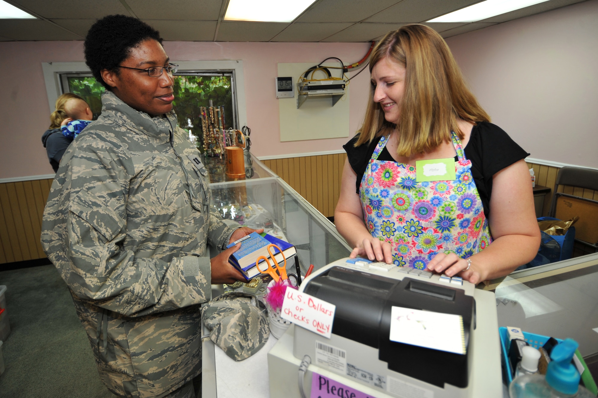 Capt. Melanie Muldrow, 51st Aerospace Medicine Squadron Public Health operations chief, purchases books while Alysha Gilbert, Osan Thrift Shop assistant manager, rings up her items at Osan Air Base, Republic of Korea, Sept. 24, 2013. Donations provide all of the items in the shop and 100 percent of the earnings are given to the Osan Enlisted and Officer Spouses’ Clubs for distribution to various military charities and scholarship programs. (U.S. Air Force photo/Staff Sgt. Emerson Nuñez)