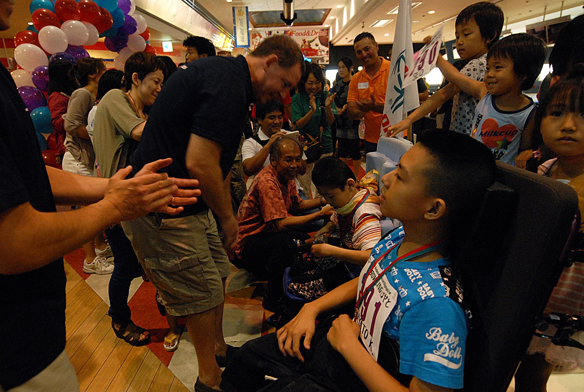 U.S. Air Force Brig. Gen. James Hecker, 18th Wing commander, presents participation medals to athletes at the Kadena Special Olympics bowling event in Mihama, Okinawa, Japan, Sept. 21, 2013. KSO athletes played a full game while being cheered on by family and military volunteers. This bowling event was one of several to precede the 14th annual KSO, which is scheduled to take place Nov. 2. (U.S. Air Force photo by Staff Sgt. Lauren Snyder)