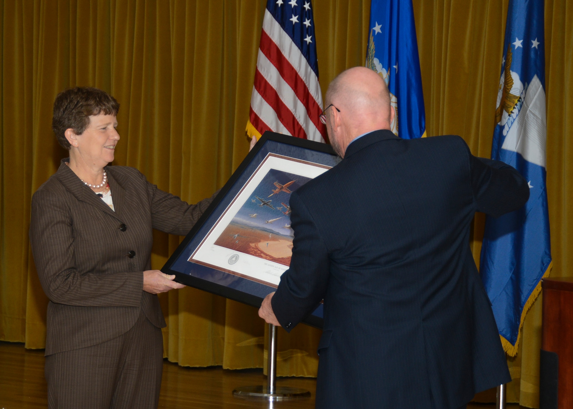 Dr. Eileen Bjorkman is presented a going away present by Dr. Davy Belk, Air Force Test Center executive director, during a farewell ceremony at Club Muroc Sept. 24. Bjorkman is retiring from her position as AFTC technical advisor after more than 30 years with the government and military. (U.S. Air Force photo by Rebecca Amber)