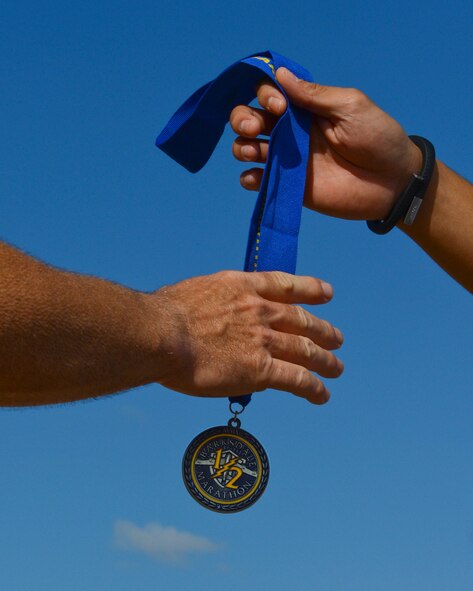 A participant of the Barksdale Half Marathon grabs a medal on Barksdale Air Force Base, La., Sept. 21, 2013. Runners were given half marathon completion medals as they crossed the finish line. After the run, organizers provided fresh fruit and sports drinks for the attendees. (U.S. Air Force photo/Senior Airman Micaiah Anthony)
