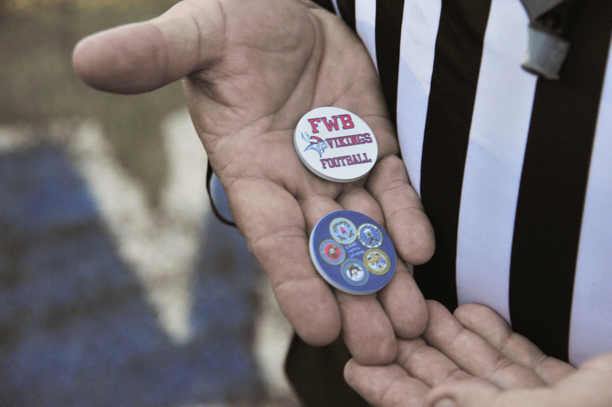 A referee displays the coins used for the coin toss at a high school football game in Fort Walton Beach, Fla., Sept. 20, 2013. Military members were invited to perform the coin toss. (U.S. Air Force photo /Airman 1st Class Andrea Posey)