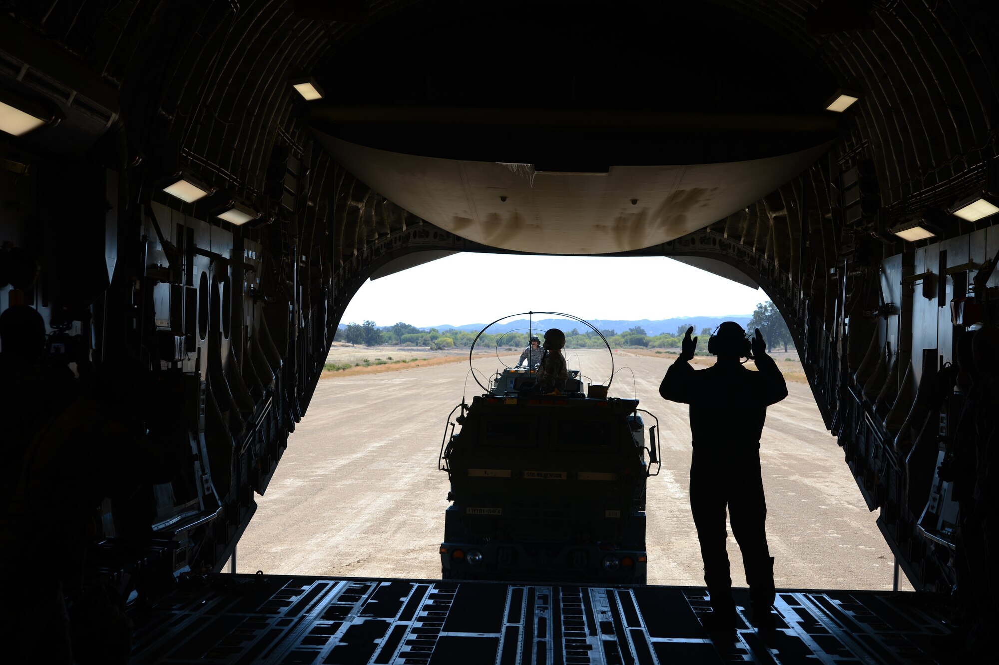 Tech. Sgt. Josh Piper, 4th Airlift Squadron instructor loadmaster, directs two M142 High Mobility Artillery Rocket System crews back onto a C-17 Globemaster III aircraft Sept. 17, 2013, at Schoonover, Calif. Within 45 minutes of landing in Schoonover, Airmen, Soldiers and artillery were airborne again and headed back to McChord Field following a successful simulated live-fire. (U.S. Air Force photo/Airman 1st Class Jacob Jimenez)