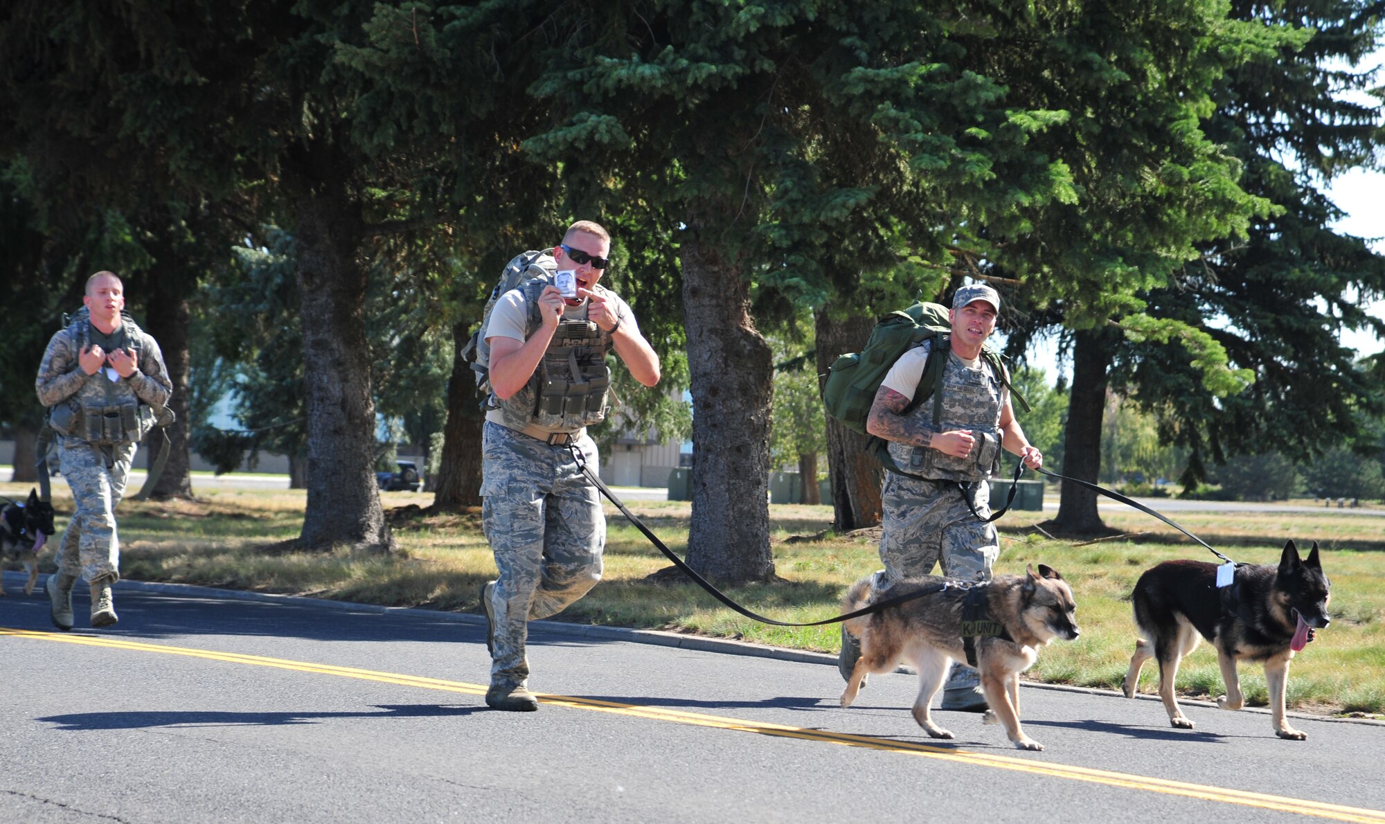 Members of the 92nd Security Forces Squadron, military working dog handlers, run toward the finish line during the “Ruck for the Missing 5K” in honor of Prisoner of War/Missing in Action Recognition Day at Fairchild Air Force Base, Wash., Sept. 20. . (U.S. Air Force photo by Staff Sgt. Michael Means/Released)
