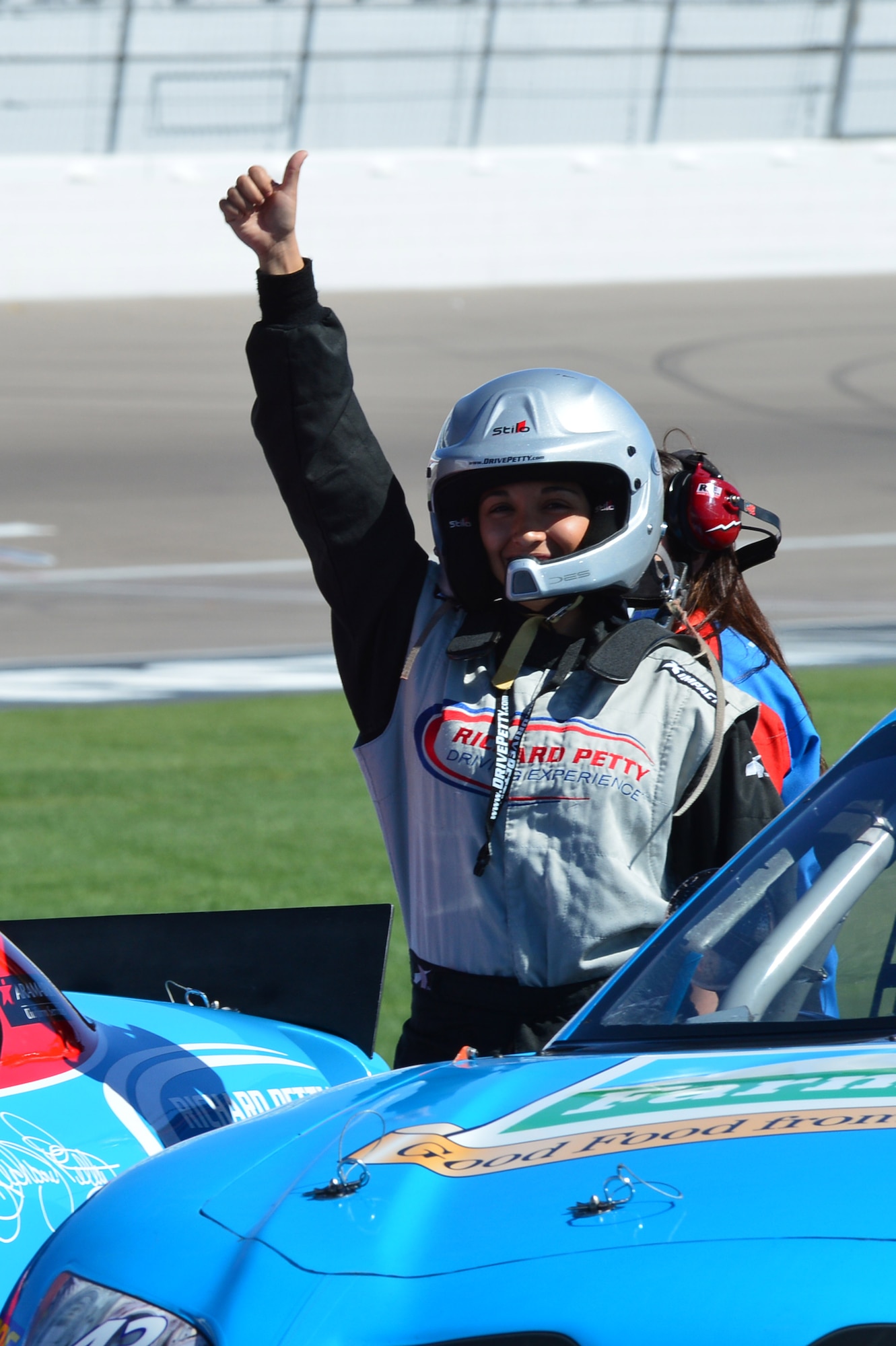 Senior Airman Rachel Maxwell, 99th Air Base Wing radio and television broadcaster, gives a thumbs up before driving a NASCAR stock car during the Richard Petty Diving Experience at the Las Vegas Motor Speedway in Las Vegas, Nev., Sept. 22, 2013. The event was sponsored by Nellis Outdoor Recreation Single Airmen Incentive Program and like other events it was provided at little or no cost to the participants. (U.S. Air Force photo by Staff Sgt. N.B.) 
